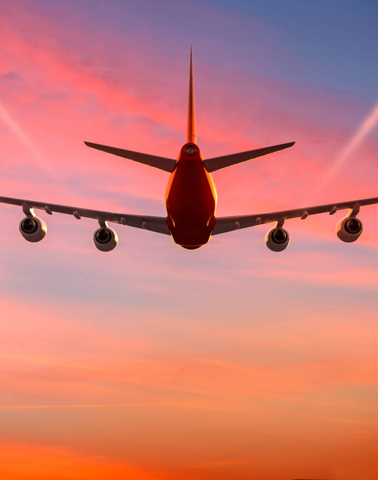 Airplane flying in the sky at sunset with vapor trails